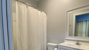 A bathroom with a white toilet, a white sink, and a shower curtain.
