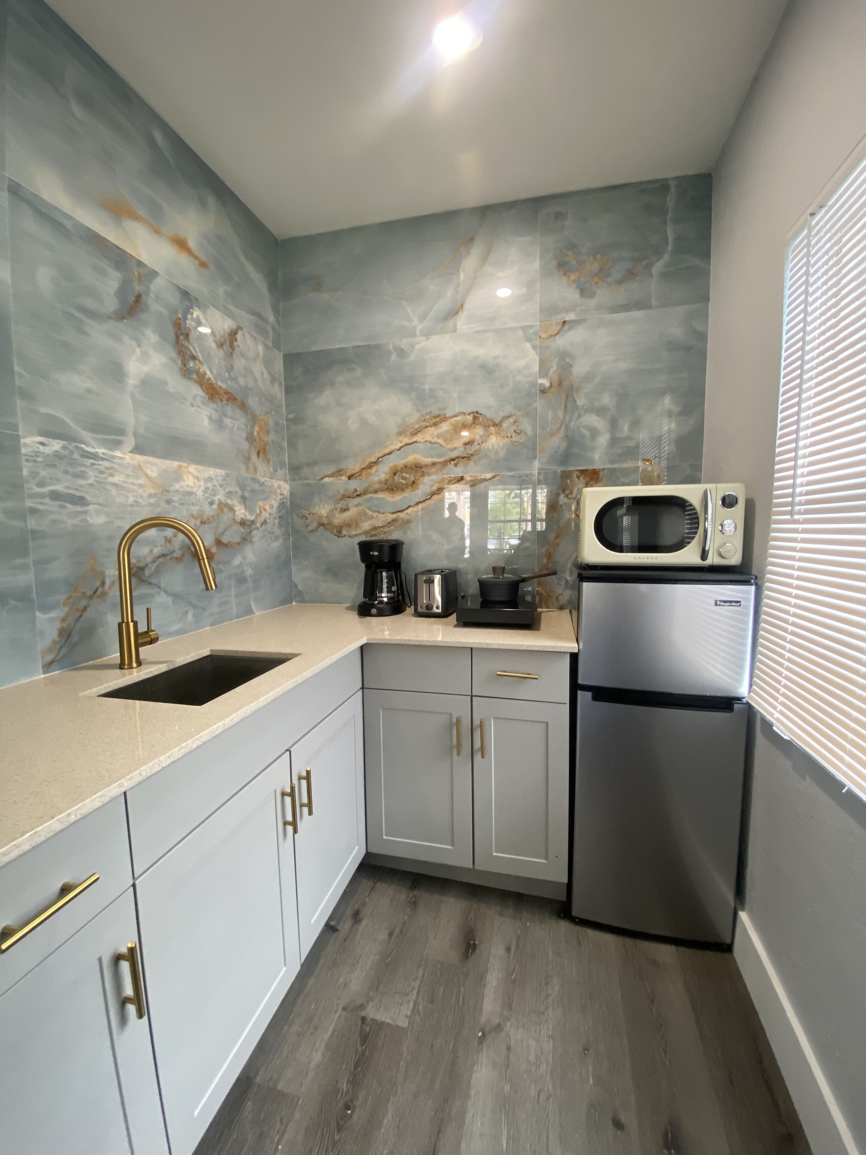 A compact kitchen with a sink, a coffee maker, a microwave, and a refrigerator.