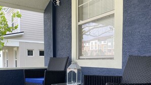 A covered patio area with wicker furniture and a clear glass table. - Bella Breeze (Sanford)