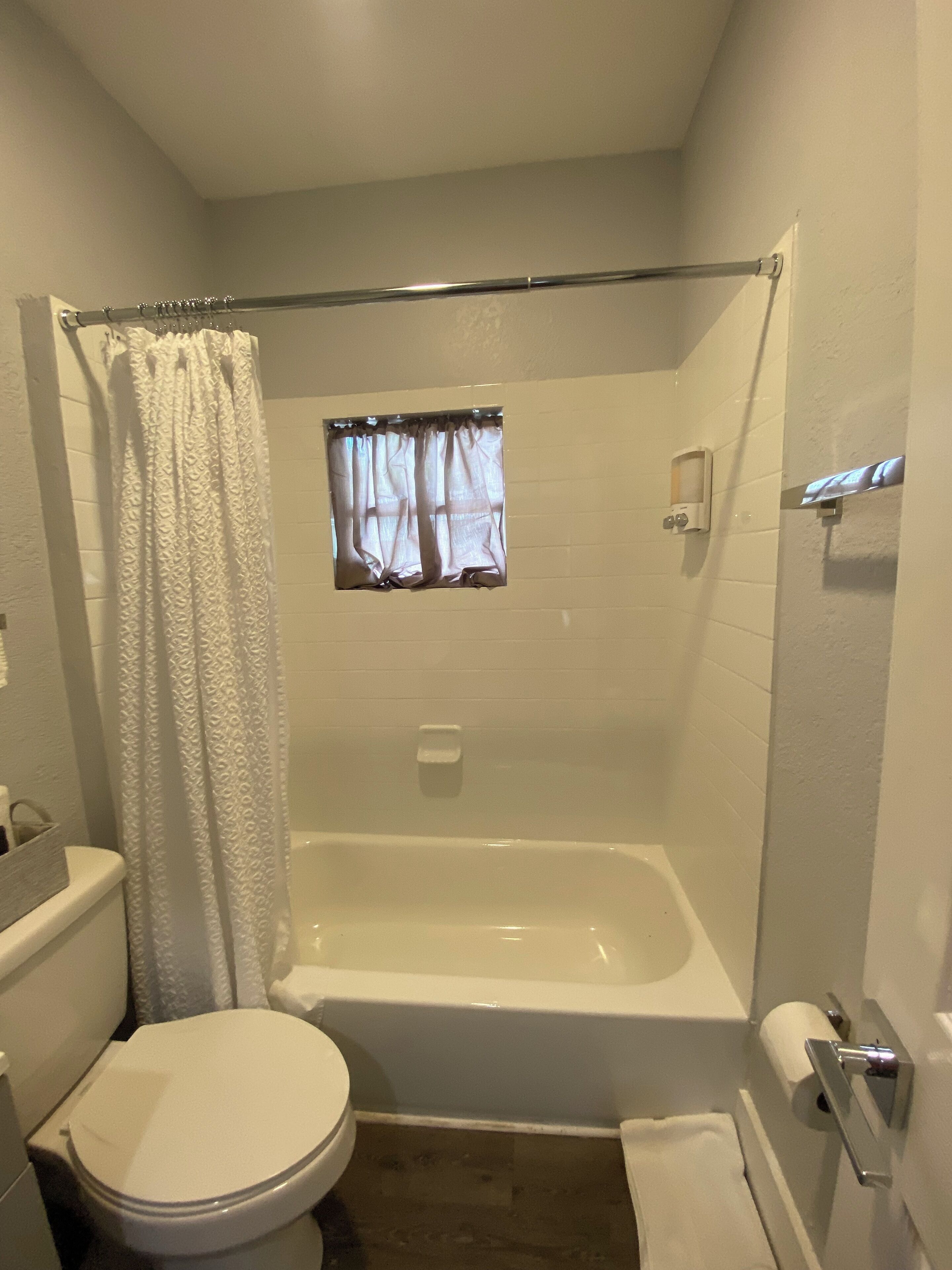 Un baño con bañera, inodoro y cortina de ducha.