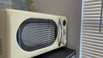 Une radio Galanz vintage, posée sur une étagère noire, devant un mur à la texture particulière.