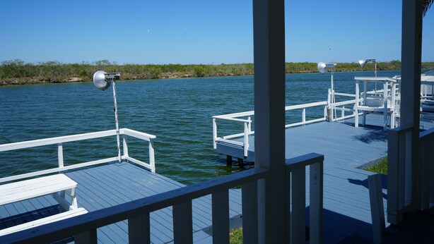 A wooden dock extending over calm water, with a white railing and benches. - Texas themed cabin with a Shared fishing pier Not waterfront (Rio Hondo)