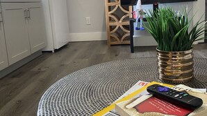 A round table with a metal mesh top, a remote control, a book, and a potted plant. - The Cherry Blossom (Sanford)