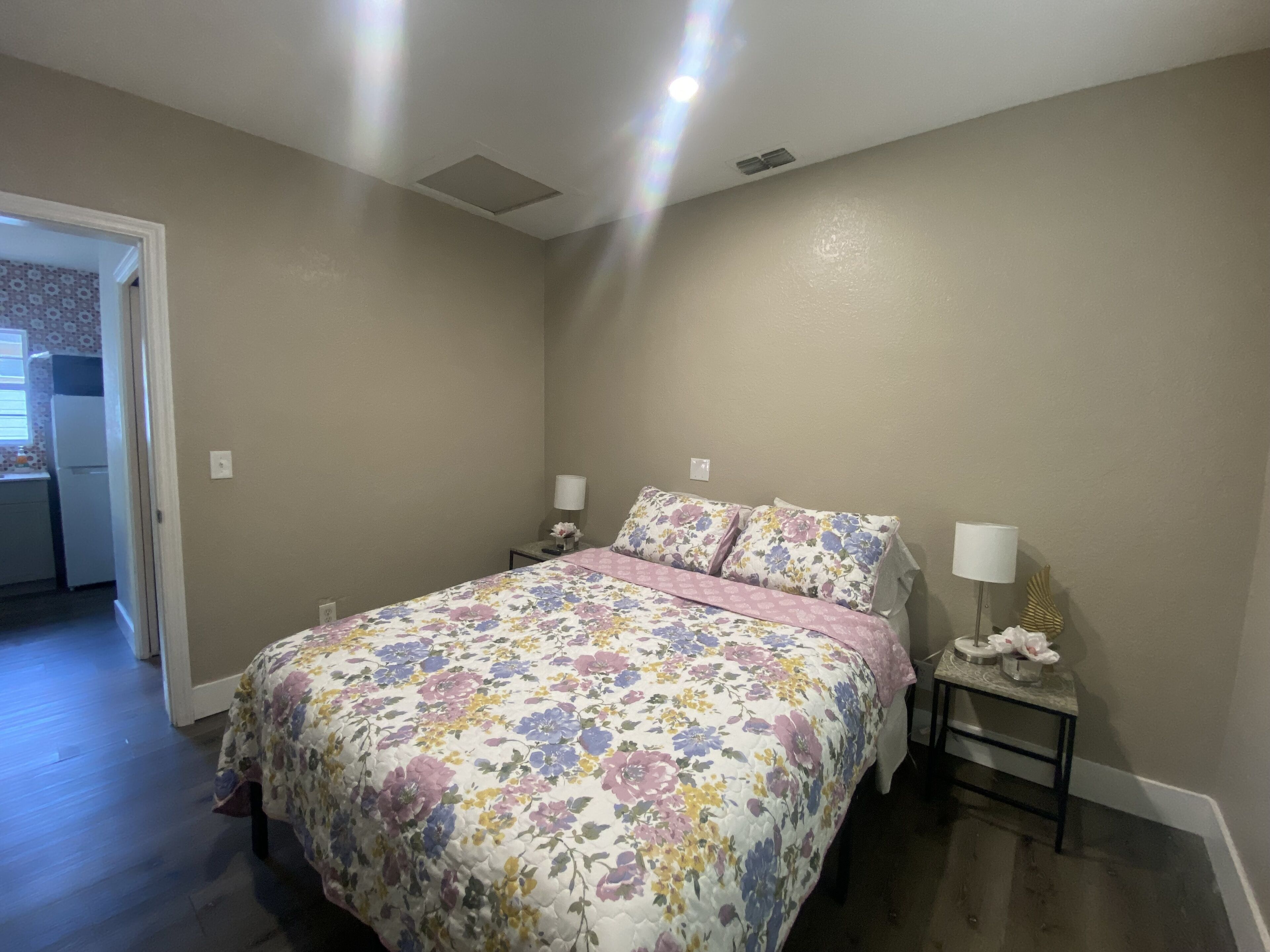 Una camera da letto con una coperta da letto a fiori, due abat-jour e un comodino con lampada.
