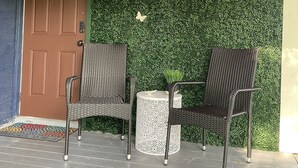 A porch with two wicker chairs, a small round table, and a neon sign reading "The Cherry Blossom". - The Cherry Blossom (Sanford)
