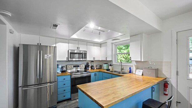 A modern kitchen with a central island, stainless steel appliances, and blue cabinetry. - Home in Kanab with Game Room. Sleeps 10, Pets OK! (Kanab)