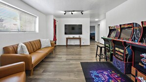 A living room with a brown leather sofa, a flat-screen TV, and arcade games. - Home in Kanab with Game Room. Sleeps 10, Pets OK! (Kanab)