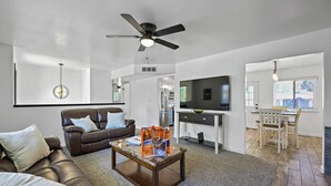 A modern living room with a leather sofa, a coffee table, a TV, and a dining area with a table and chairs. - Home in Kanab with Game Room. Sleeps 10, Pets OK! (Kanab)