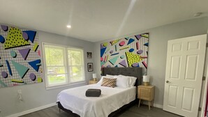 Una camera da letto con un letto, un comodino, una porta e una finestra.