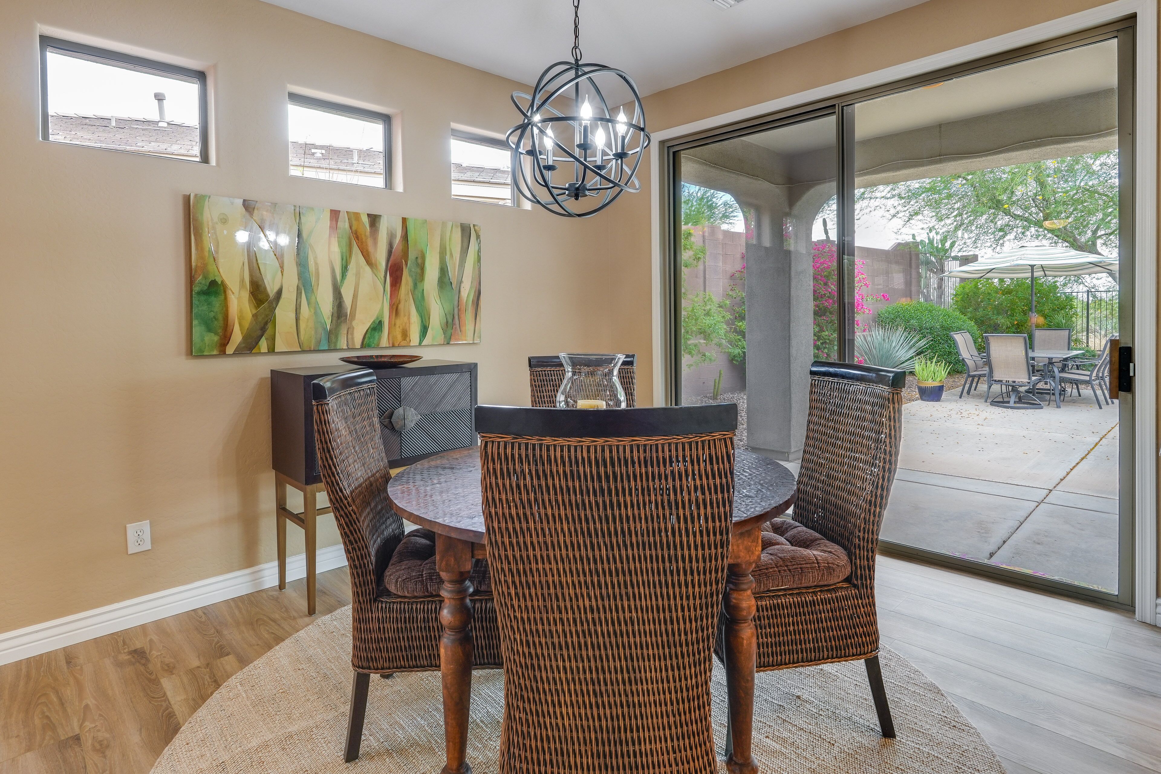 A dining area with wicker chairs, a round table, and a chandelier.