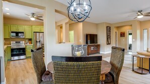 A modern kitchen with green cabinets, a dining area with wicker chairs, and a ceiling fan. - Snowbirds Welcome! Anthem Gem w/ Fairway Views (Anthem)