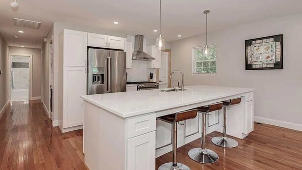 A modern kitchen with white cabinetry, stainless steel appliances, and a central island with bar stools. - Abbott Park 5 minutes to South End- 2 BR (Charlotte)