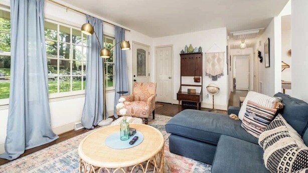 A living room with a sofa, a round table, a patterned rug, a chair, and a cabinet. - Comfy cozy laid back cottage (Charlotte)