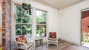 A room with two wicker chairs, a small table, and a hanging plant. - Comfy cozy laid back cottage (Charlotte)