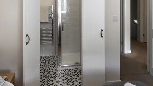 Un dormitorio con cama, un baño con ducha y un pasillo.