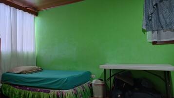 Quarto com cama, escrivaninha e parede verde.