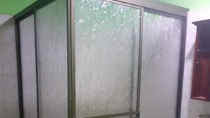 Casa de banho com cabine de duche em vidro, lavatório branco e paredes verdes.