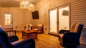 Un patio techado con suelo de madera, muebles de mimbre y una mesa con un farol.