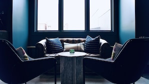 Ein modernes Zimmer mit einem Ledersofa, zwei schwarzen Ohrensesseln und einem Marmortisch.