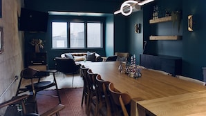 Ein modernes Esszimmer mit einem Holztisch und Stühlen, einer Couch und einem an der Wand befestigten Fernseher.