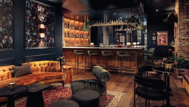 Eine Bar mit einer Theke, Barhocker und Regalen voller Flaschen.