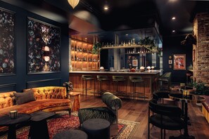 Eine Bar mit einer Theke, Barhocker und Regalen voller Flaschen.