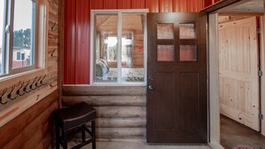 L’intérieur d’une cabane en bois, avec une grande fenêtre, une porte et un banc.