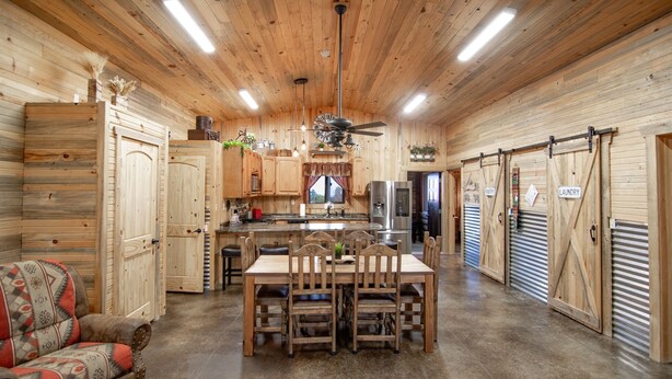 Un intérieur rustique en bois comprenant un coin repas, une cuisine et des portes coulissantes portant les inscriptions « GARDEMANGER » et « BUANDERIE ».