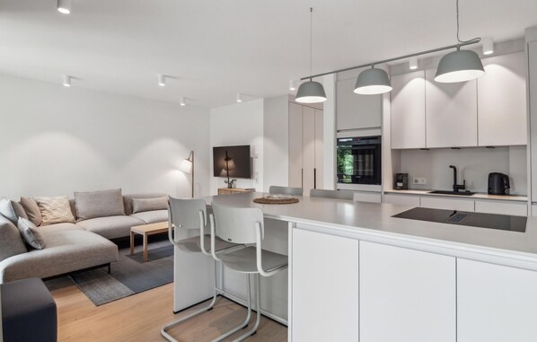 Een moderne keuken met witte kasten, een centraal eiland en hanglampen.