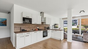 Une cuisine moderne avec des meubles blancs, un plan de travail en bois et un four encastré.