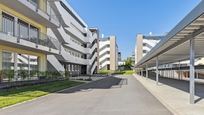 Un immeuble résidentiel moderne à plusieurs étages, doté d’une cour intérieure, de balcons et d’une galerie couverte.