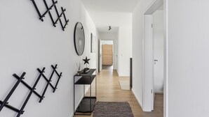 Un couloir au design moderne, agrémenté d’une étagère en métal noir, d’un miroir et d’une décoration en forme d’étoile sur le mur.