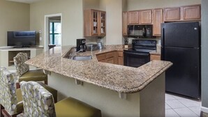A kitchen with granite countertops, wooden cabinets, a black refrigerator, and a built-in microwave. - 2Bed/2Bath - Smoky Mountains Retreat! Gorgeous Views, Pools, + More! (Sevierville)