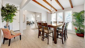 Zona pranzo con tavolo e sedie in legno, un lampadario e piante in vaso.