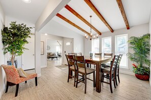 A dining area with a wooden table and chairs, a chandelier, and potted plants.