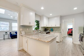 A modern kitchen with white cabinets, a marble countertop, and a built-in island.