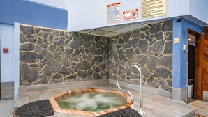 Een wellnessruimte met stenen muren, een jacuzzi en een metalen kraan.