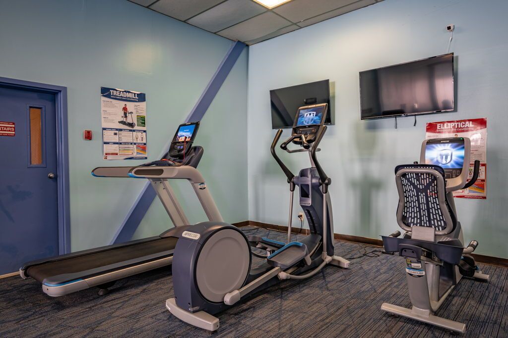 Une salle de remise en forme équipée de tapis de course, de vélos elliptiques et d’un vélo d’appartement.