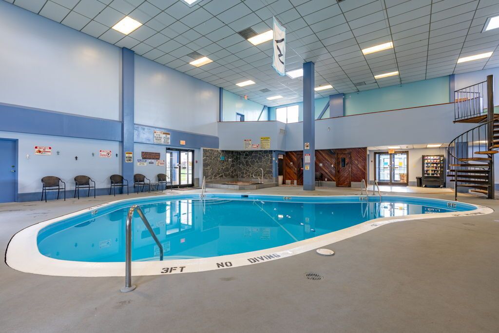 Indendørs swimmingpool med et 'Ingen dykning'-skilt, omgivet af stole og en trappe.