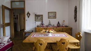 Un comedor con una mesa de madera, sillas, un frutero, una lámpara y adornos en la pared.