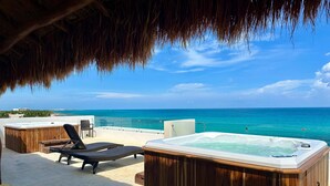 Una terraza en la azotea con un jacuzzi, sillones de descanso y vistas al océano.