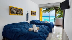 Habitación de hotel con dos camas, un televisor de pantalla plana, obras de arte en las paredes y vista al océano.