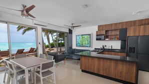 Una cocina moderna con una isla grande, un comedor con mesa y sillas, y vista al océano.