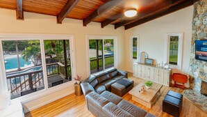 A spacious living room with a large leather sectional sofa, wooden flooring, and a stone accent wall. - Unique Home Resort W/ Coolest Amenities and Games! (Jensen Beach)