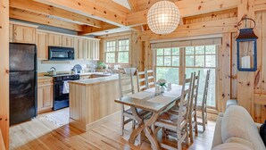 L’intérieur d’un chalet en bois comprend une cuisine, un coin repas et une grande fenêtre.