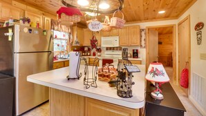 A kitchen with wooden cabinets, a stainless steel refrigerator, a white microwave, and a black countertop. - Virginia Mountain Cabin w/ Decks & Fireplaces (Fulks Run)