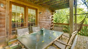 A wooden cabin with a glass table and chairs, a hammock, and a view of the forest. - Virginia Mountain Cabin w/ Decks & Fireplaces (Fulks Run)
