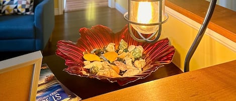 A room with a wooden table, a decorative lamp with a flower-shaped base, and a bowl of seashells.