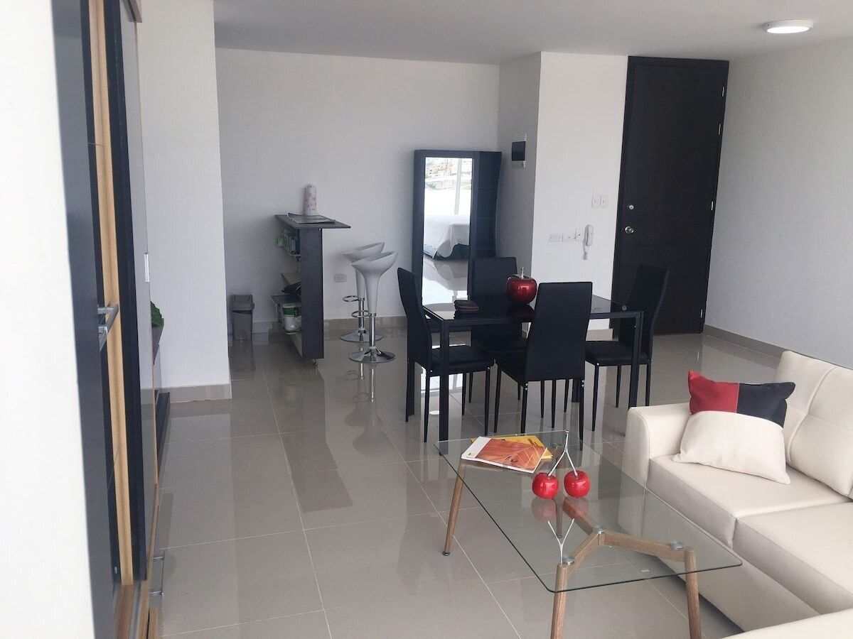 Un salon moderne avec une table basse en verre, un canapé et un coin repas comprenant des chaises et une table.