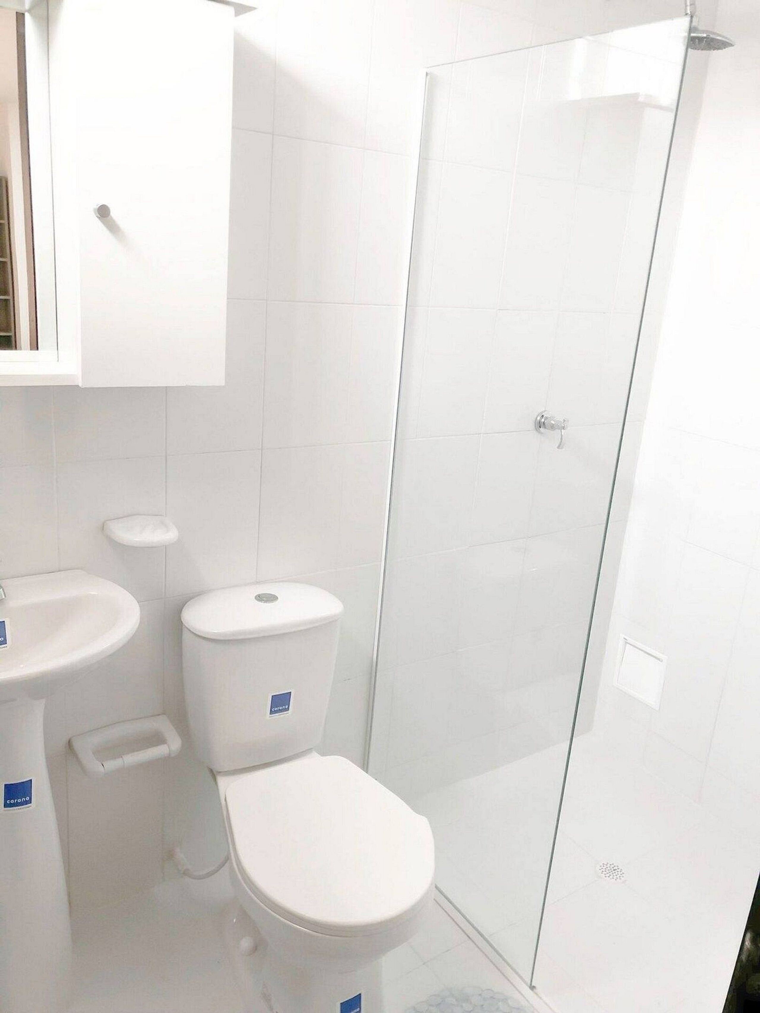 A bathroom with a toilet, sink, and glass shower enclosure.